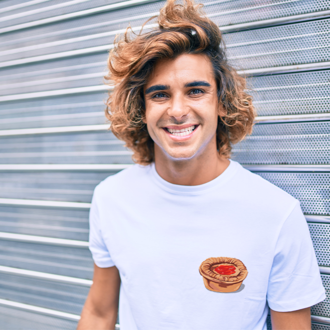 Man wearing a white t-shirt with printed meat pie design  standing in front of a metallic shutter.